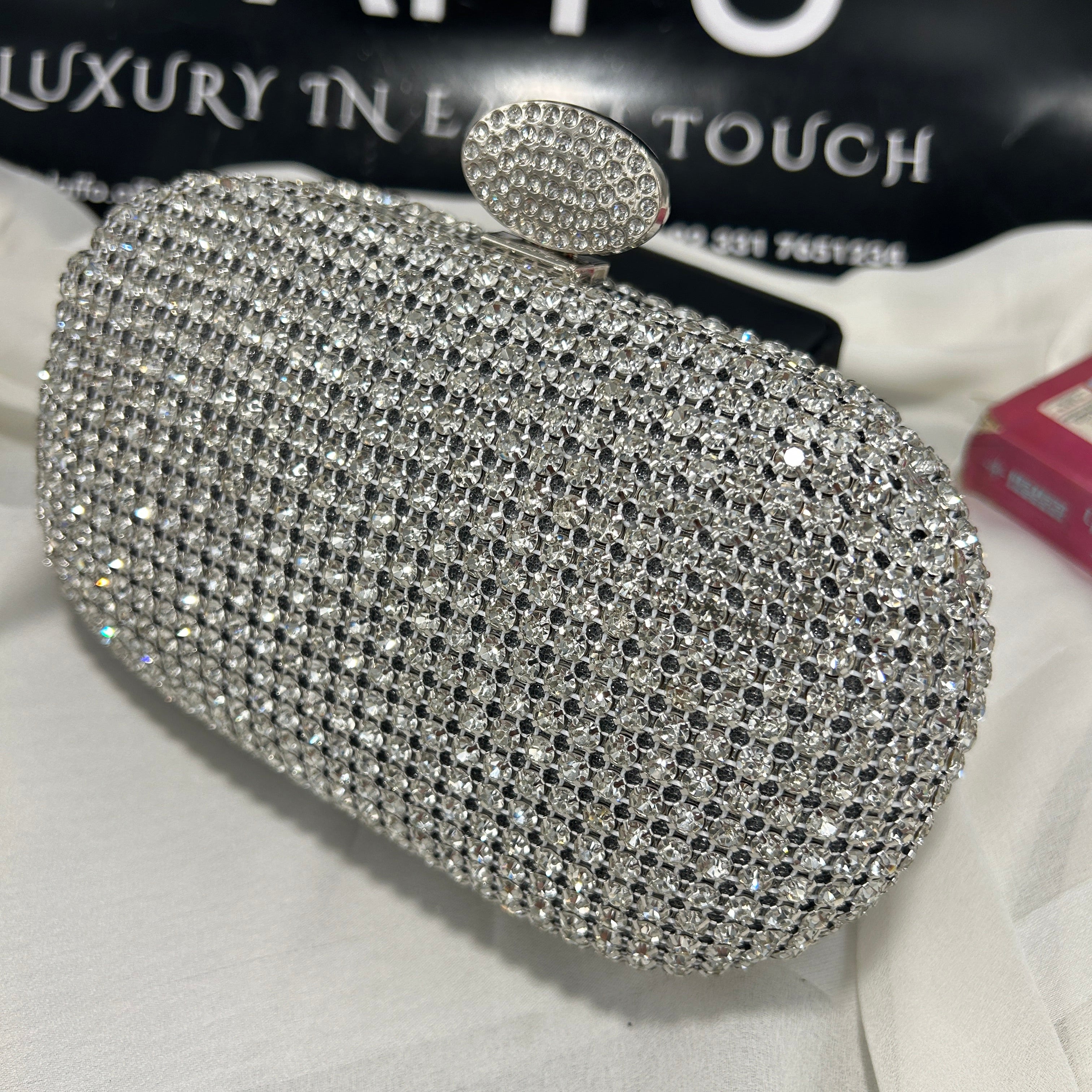 Silver glittery clutch on a white surface with a blurred background
